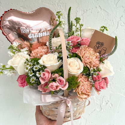 Bouquet of flowers in a basket with a heart-shaped balloon and card 